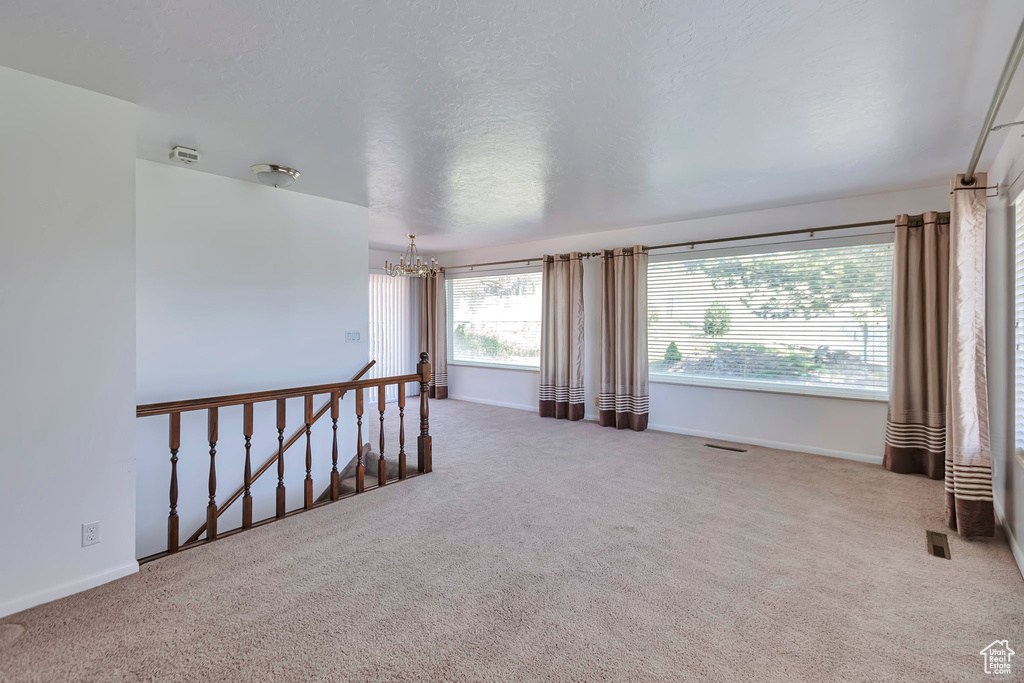 Spare room with a chandelier, carpet flooring, and baseboards