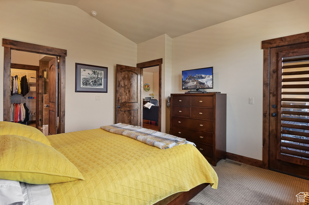 Bedroom with carpet floors, lofted ceiling, a walk in closet, a closet, and baseboards