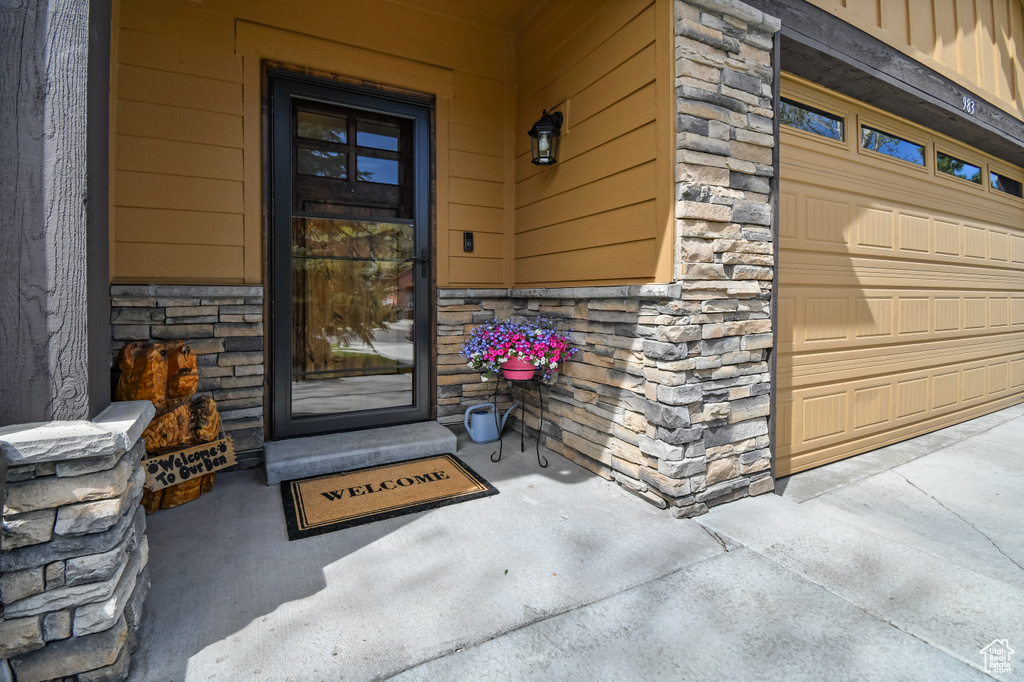 Doorway to property with stone siding and a garage