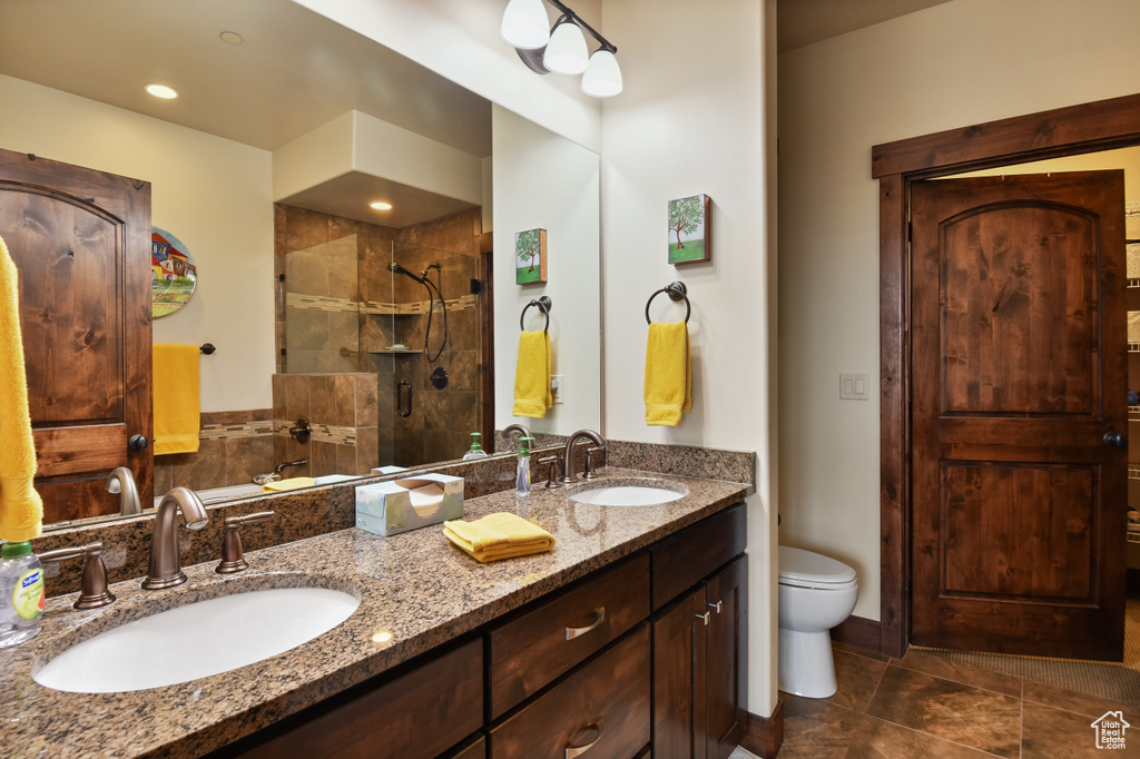 Full bathroom with a tile shower, double vanity, toilet, and tile patterned floors