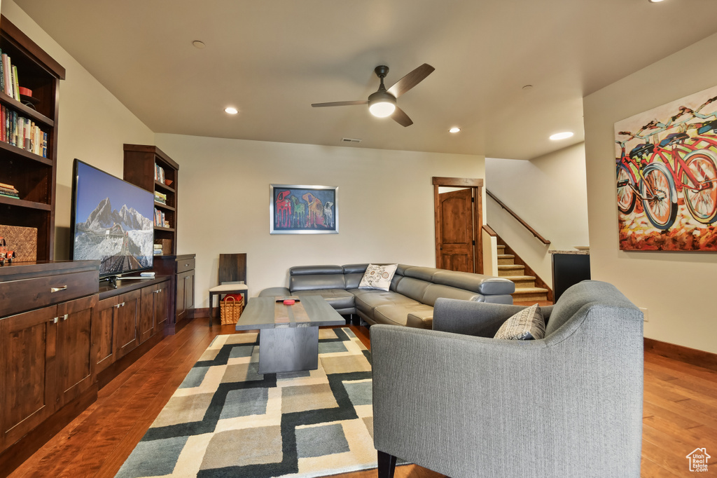 Living area with dark wood-type flooring, stairs, baseboards, and recessed lighting