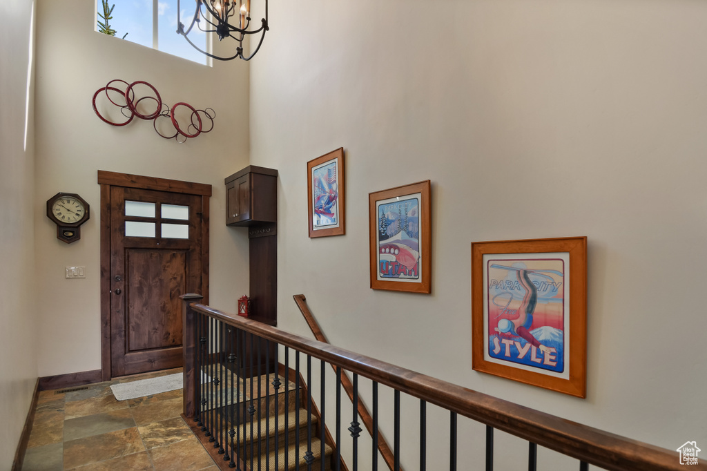 Foyer entrance featuring a chandelier, a towering ceiling, dark stone finish flooring, and baseboards