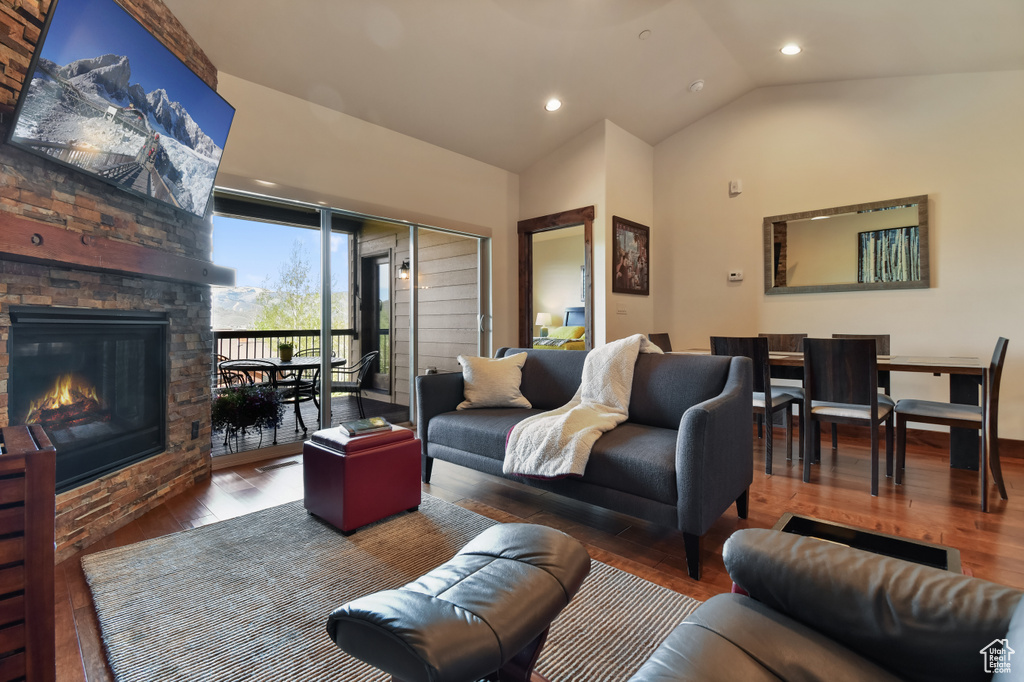 Living room with wood finished floors, vaulted ceiling, recessed lighting, and a fireplace