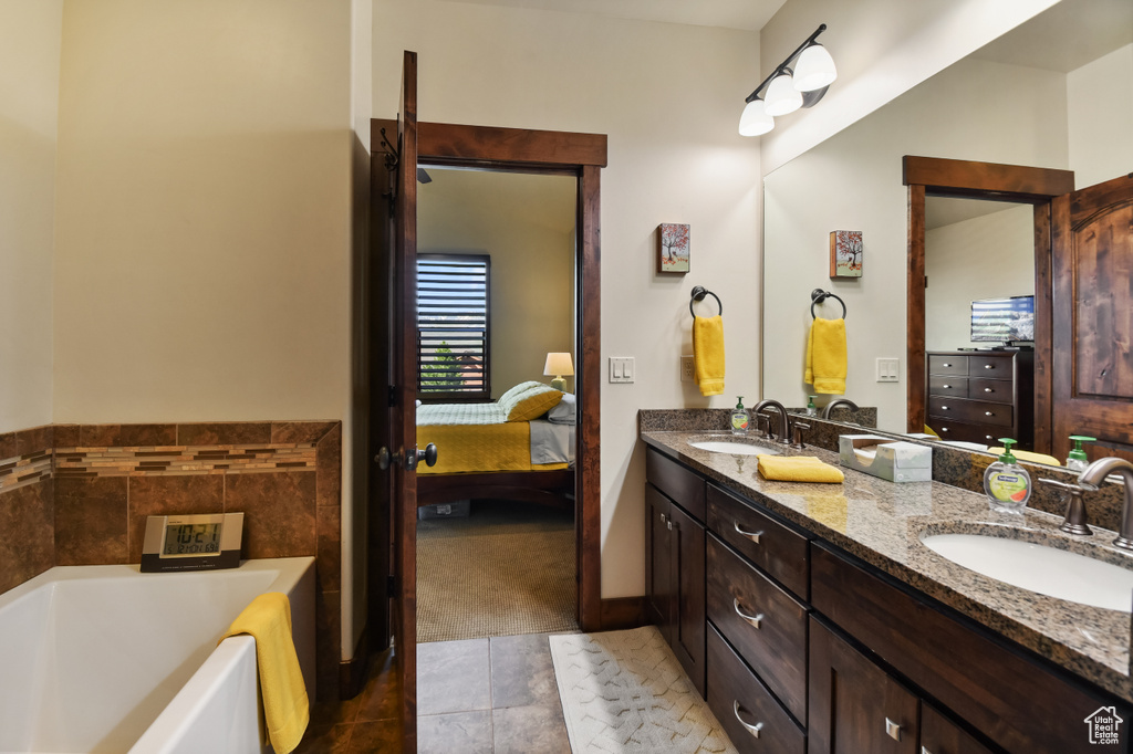 Ensuite bathroom featuring a garden tub, double vanity, and tile patterned floors