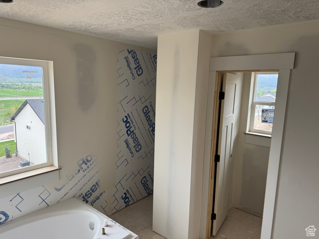 Bathroom featuring a textured ceiling and a tub to relax in