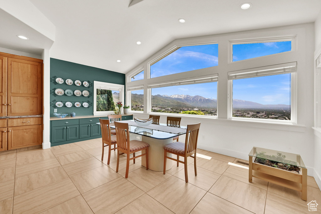 Dining room with a mountain view, recessed lighting, light tile patterned floors, and high vaulted ceiling
