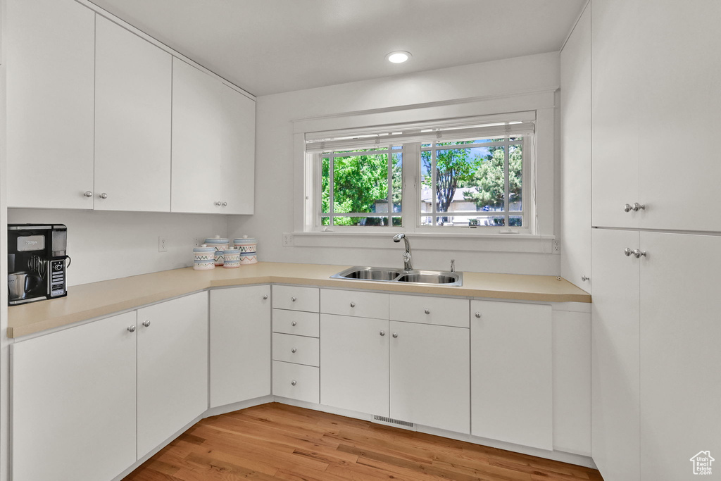 Kitchen featuring a sink, white cabinetry, light wood-type flooring, light countertops, and recessed lighting