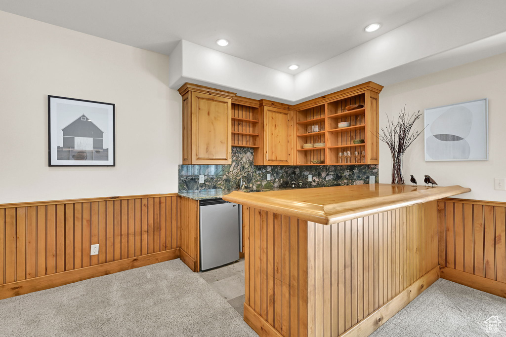 Indoor wet bar featuring dishwasher, a wainscoted wall, light colored carpet, backsplash, and wood walls