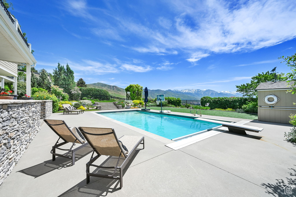 View of pool with a mountain view, a patio, and a diving board