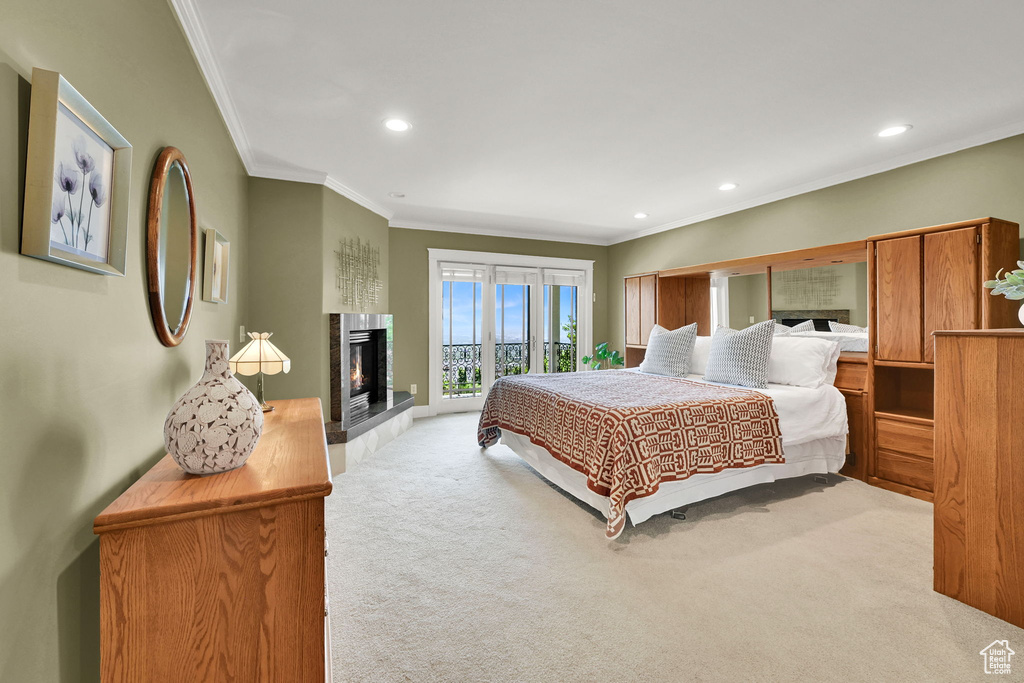 Bedroom with carpet floors, crown molding, recessed lighting, a glass covered fireplace, and access to exterior