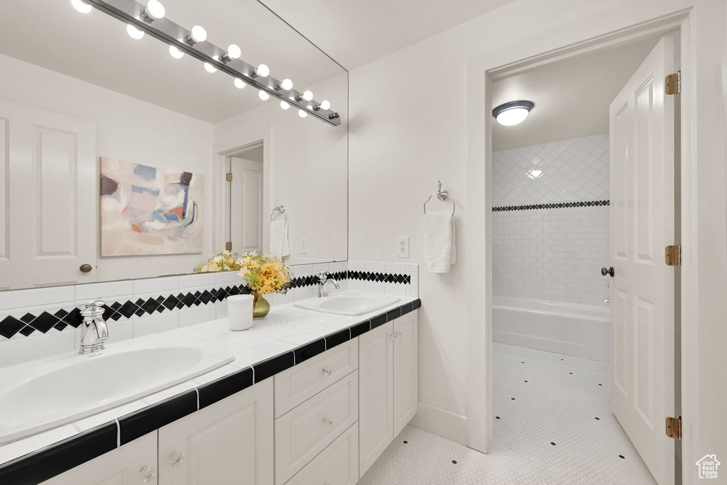 Full bathroom with double vanity, tile patterned floors, and  shower combination