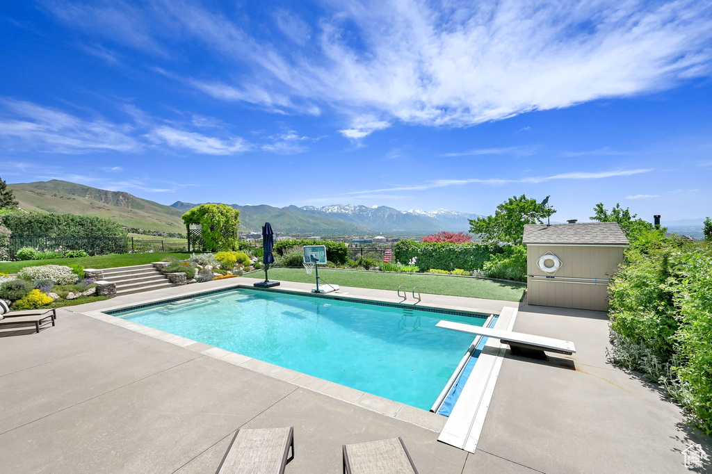 View of swimming pool with a mountain view, a patio area, and a diving board
