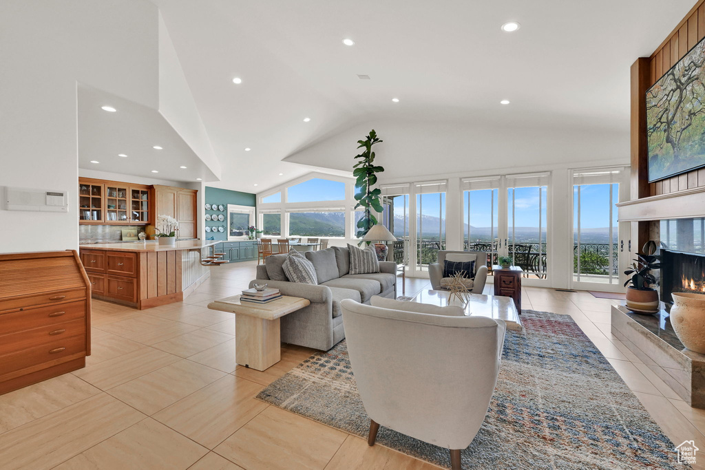 Living room with vaulted ceiling, a fireplace, light tile patterned floors, and recessed lighting