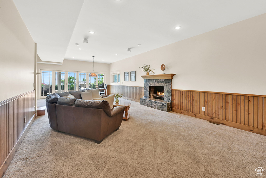 Living area with wainscoting, carpet, a stone fireplace, recessed lighting, and wood walls