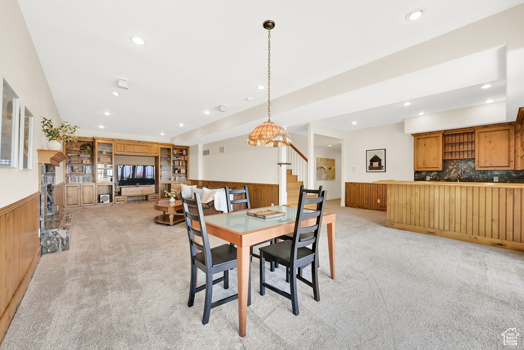 Dining room featuring light carpet, wainscoting, recessed lighting, stairway, and wood walls