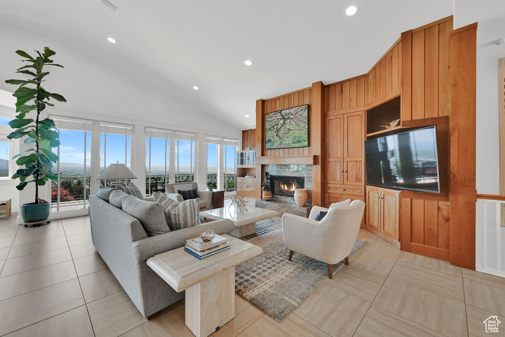 Living room featuring a lit fireplace, plenty of natural light, recessed lighting, light tile patterned flooring, and high vaulted ceiling