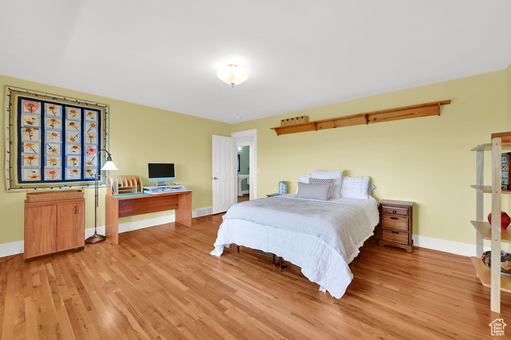 Bedroom featuring light wood-style flooring, baseboards, and a desk