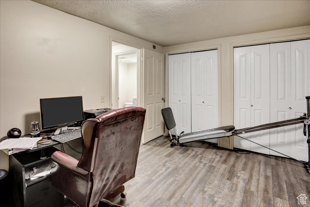 Home office with wood finished floors and a textured ceiling