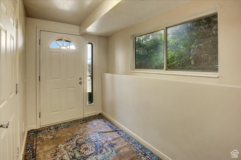 Foyer featuring baseboards and a textured ceiling