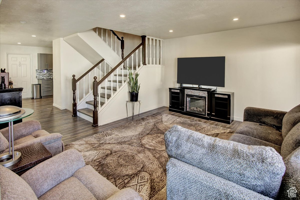 Living area with stairway, wood finished floors, recessed lighting, and baseboards