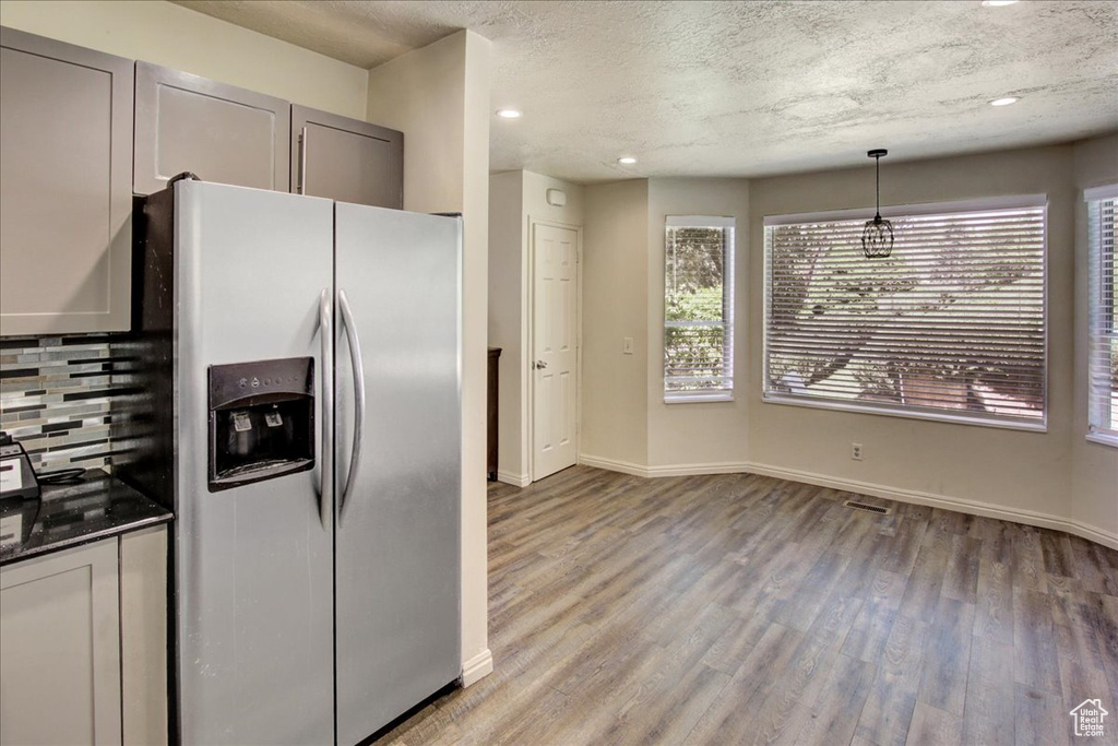 Kitchen featuring stainless steel fridge with ice dispenser, light wood-style floors, a textured ceiling, gray cabinetry, and backsplash