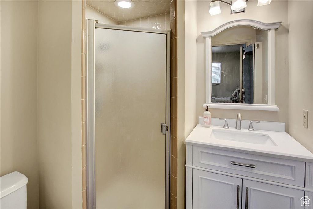 Bathroom featuring a stall shower, toilet, and vanity