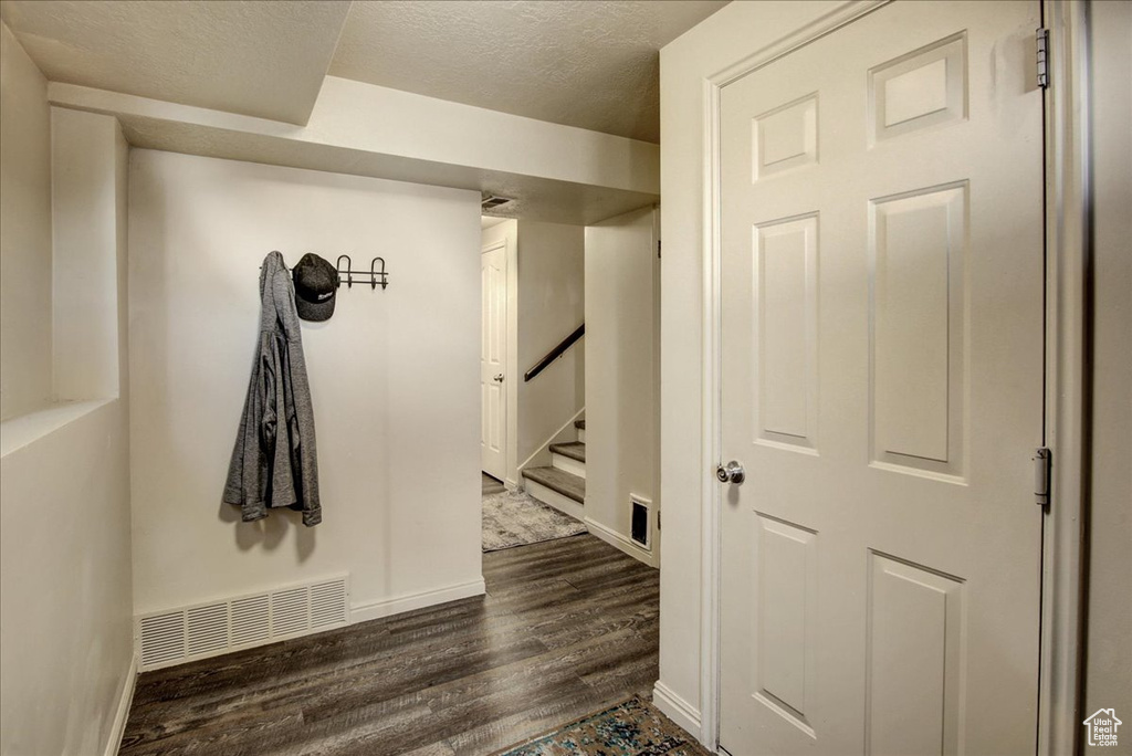 Hallway with dark wood finished floors, baseboards, a textured ceiling, and stairway