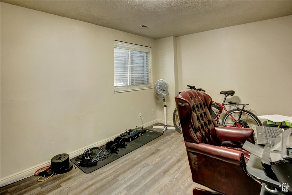 Workout room with wood finished floors, a textured ceiling, and baseboards