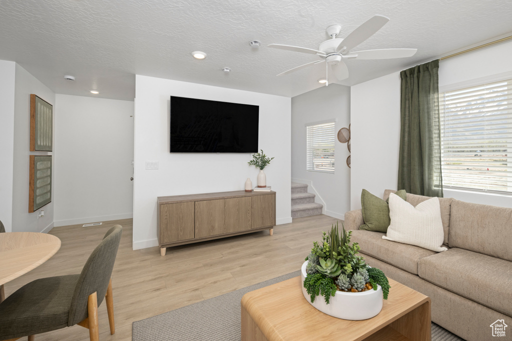Living area with light wood-style floors, recessed lighting, ceiling fan, baseboards, and a textured ceiling