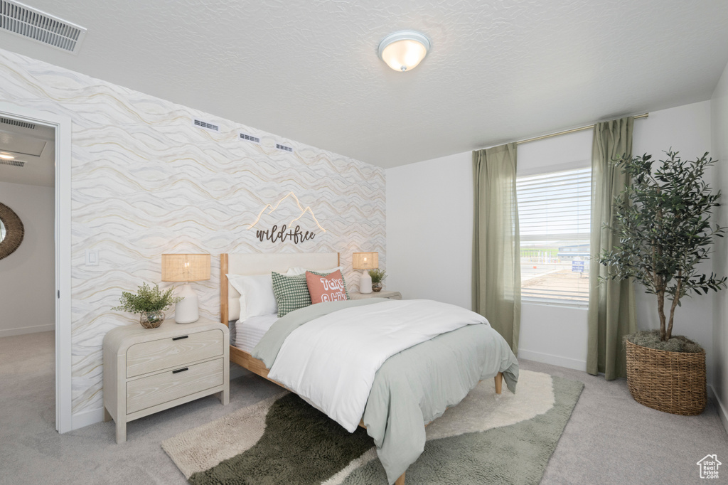 Bedroom with wallpapered walls, carpet, baseboards, and an accent wall