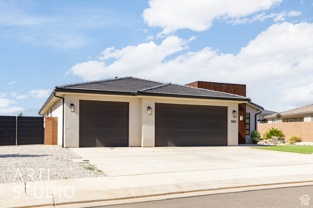 View of front facade featuring driveway, an attached garage, a tiled roof, and stucco siding
