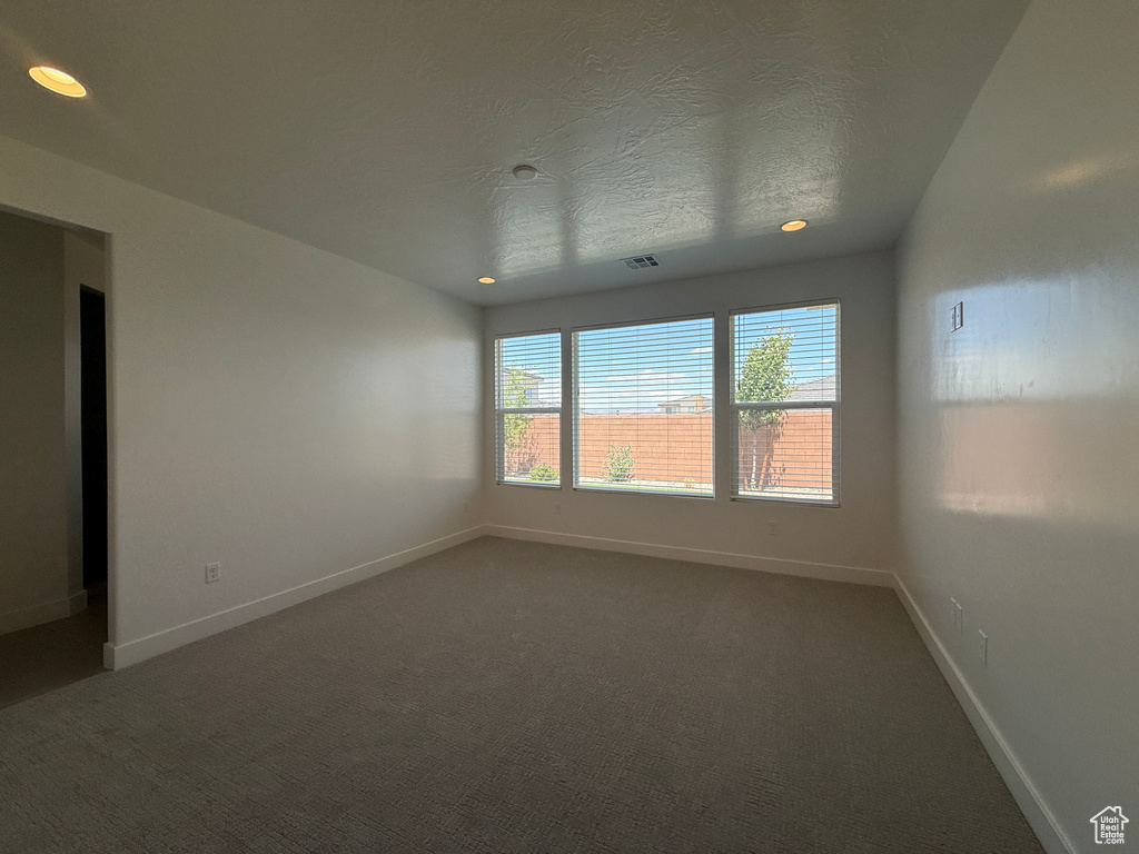 Spare room featuring baseboards, recessed lighting, and dark colored carpet