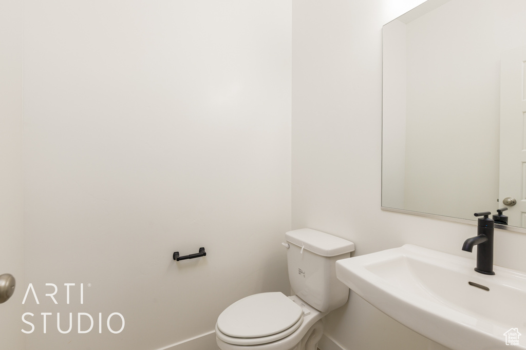 Half bathroom featuring a sink, toilet, and baseboards