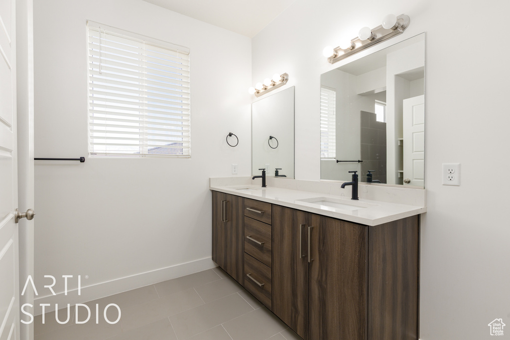 Full bath with double vanity, tile patterned floors, and baseboards