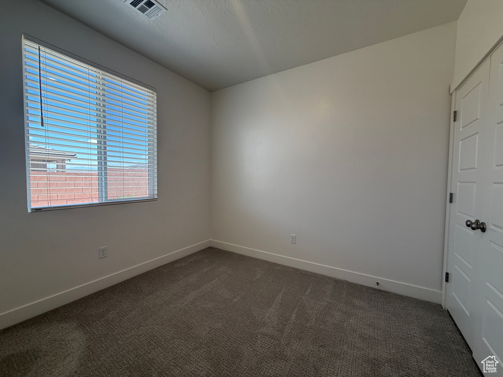 Spare room with baseboards and dark colored carpet