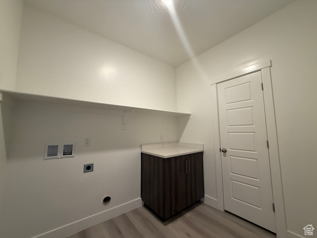 Washroom with electric dryer hookup, hookup for a washing machine, light wood-style flooring, and baseboards