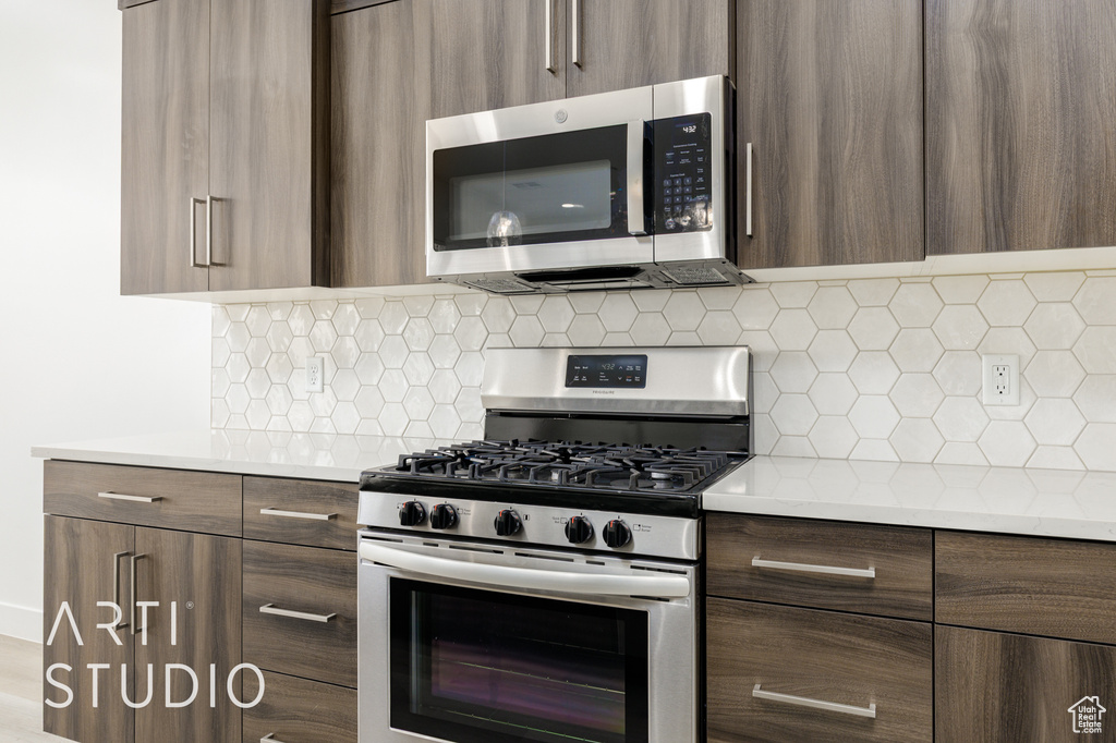 Kitchen featuring stainless steel appliances, modern cabinets, light countertops, and decorative backsplash