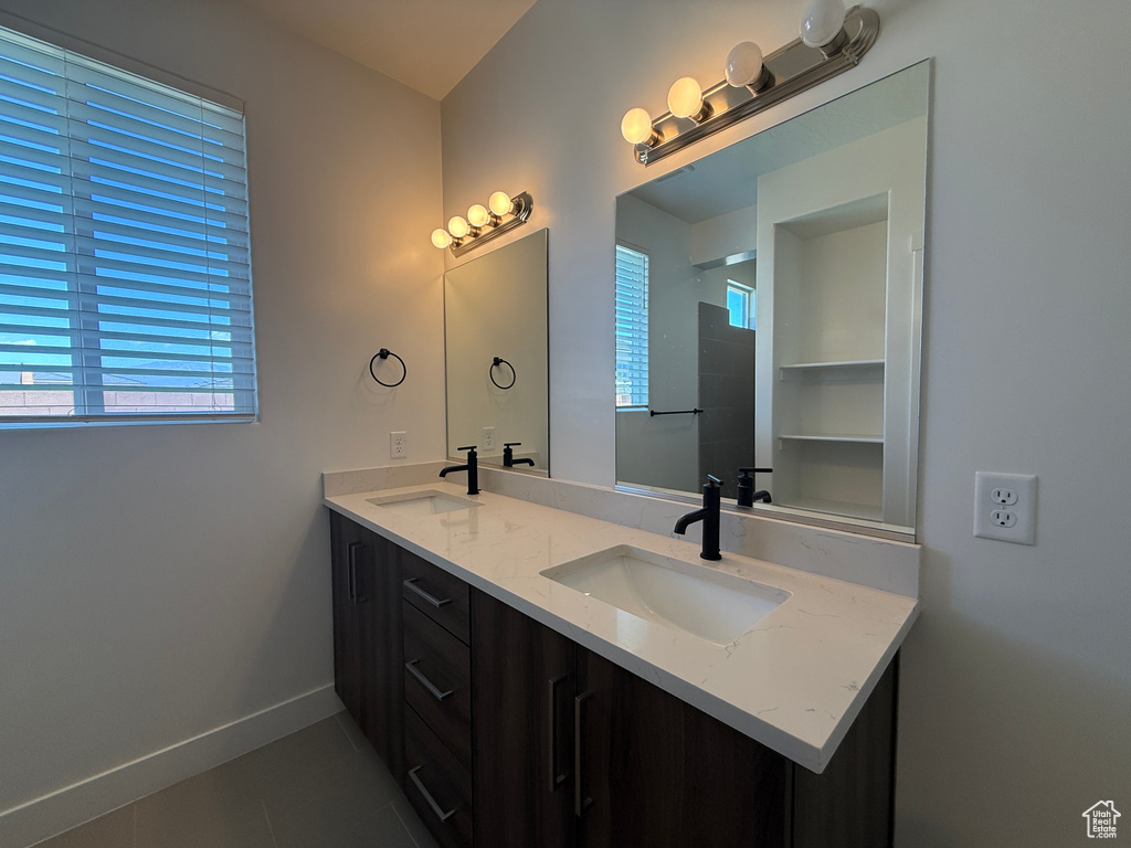 Bathroom featuring tile patterned floors, double vanity, and baseboards