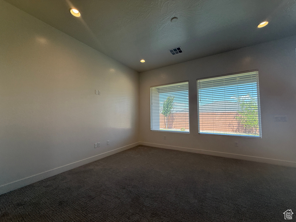Empty room with baseboards, dark colored carpet, vaulted ceiling, and recessed lighting