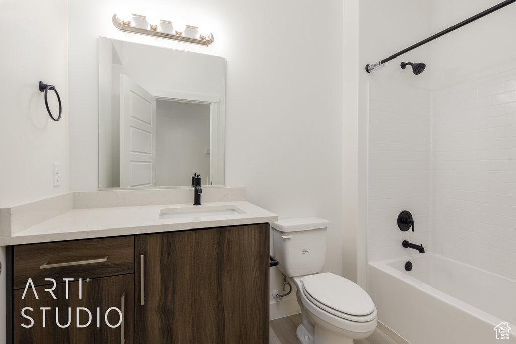 Bathroom featuring toilet, vanity, bathtub / shower combination, and wood finished floors