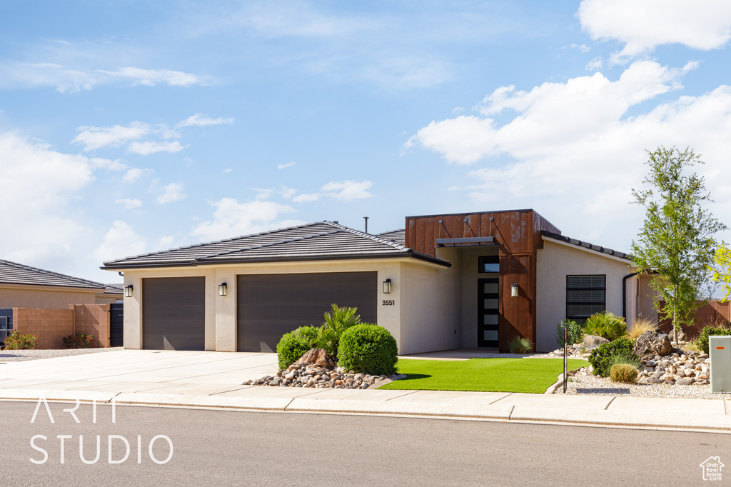 Contemporary home featuring stucco siding, driveway, a garage, and a tiled roof