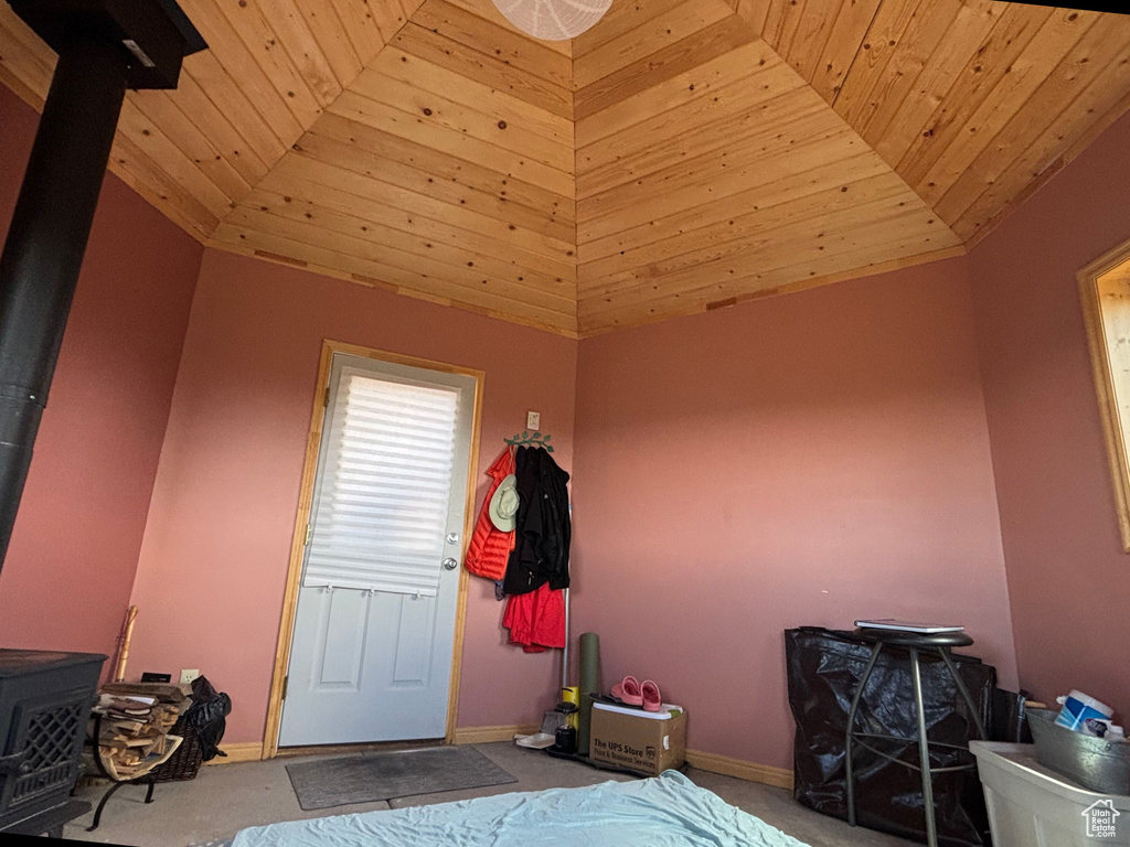Bedroom with carpet, wooden ceiling, baseboards, a wood stove, and lofted ceiling