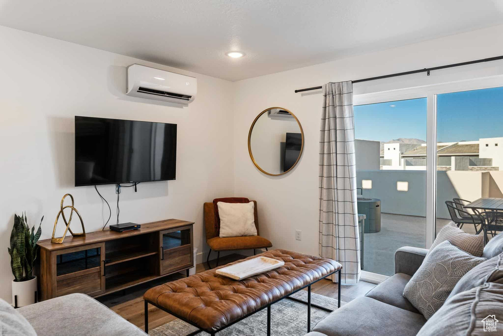 Living area featuring a wall mounted air conditioner, wood finished floors, baseboards, and recessed lighting