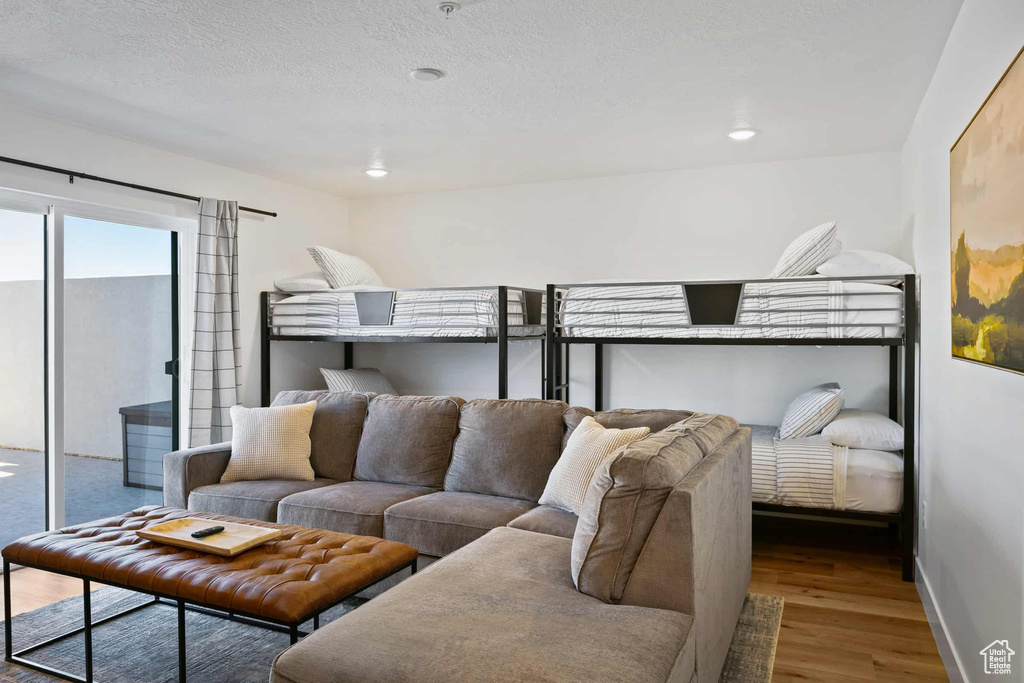 Bedroom featuring wood finished floors, access to exterior, baseboards, and a textured ceiling