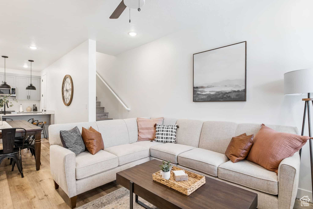 Living room with light wood finished floors, ceiling fan, stairs, and recessed lighting