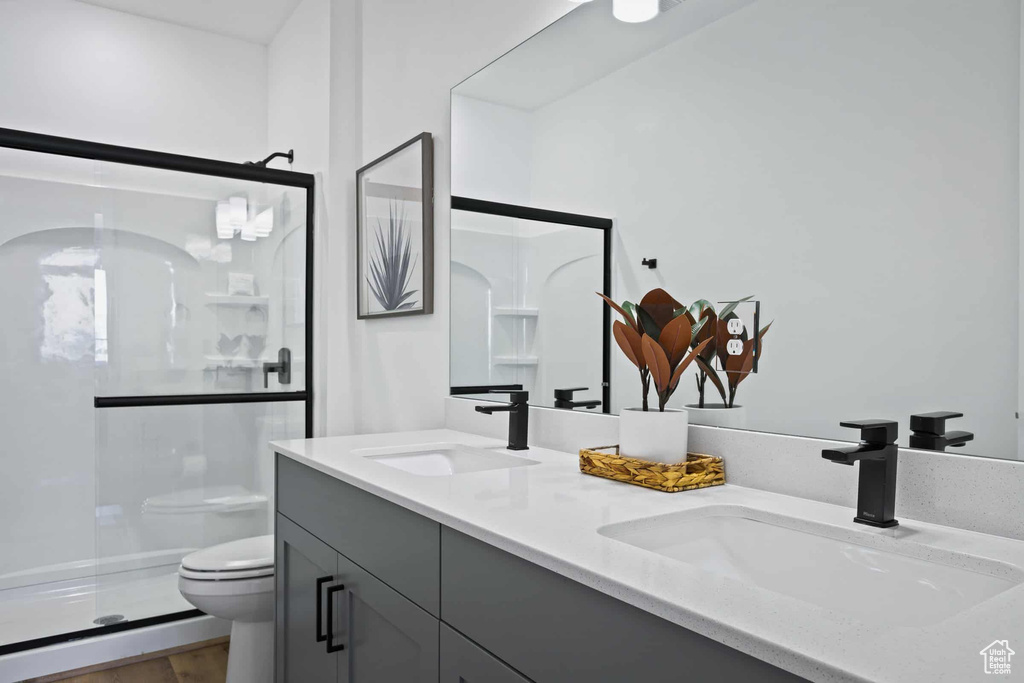 Bathroom with toilet, a stall shower, and double vanity