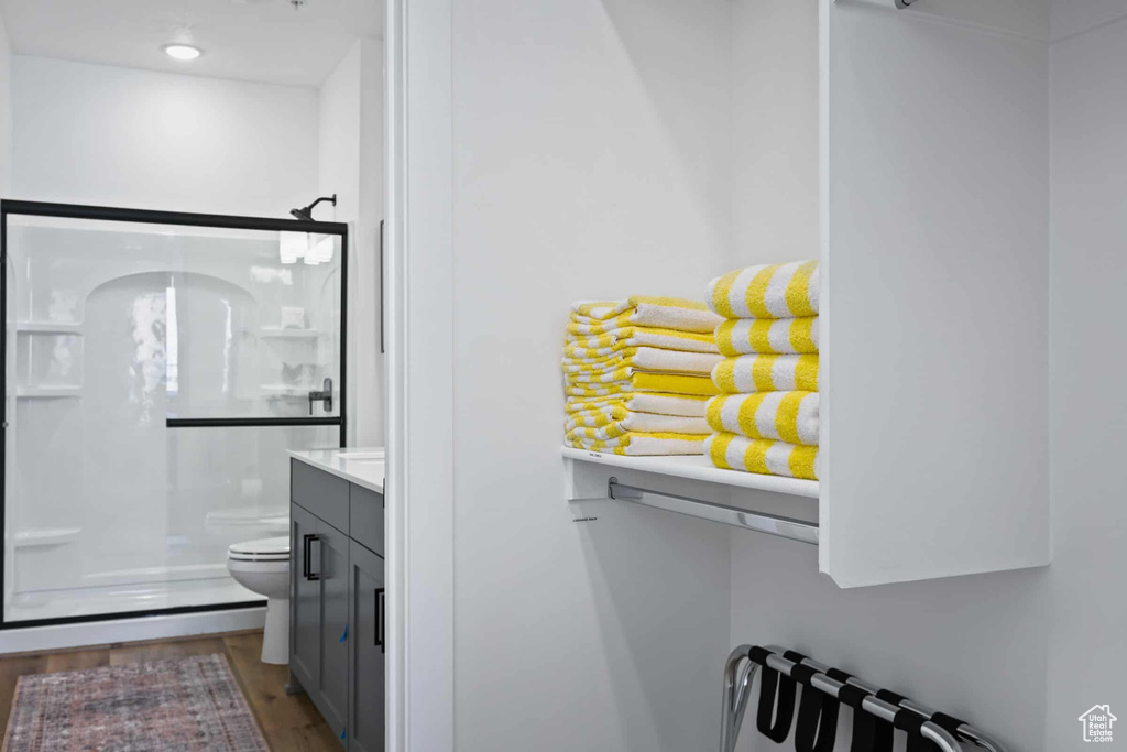 Full bath featuring a stall shower, toilet, vanity, wood finished floors, and radiator heating unit