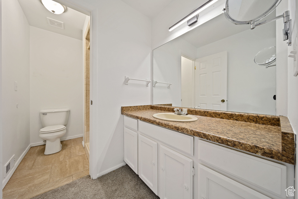 Bathroom featuring toilet, vanity, baseboards, and a shower