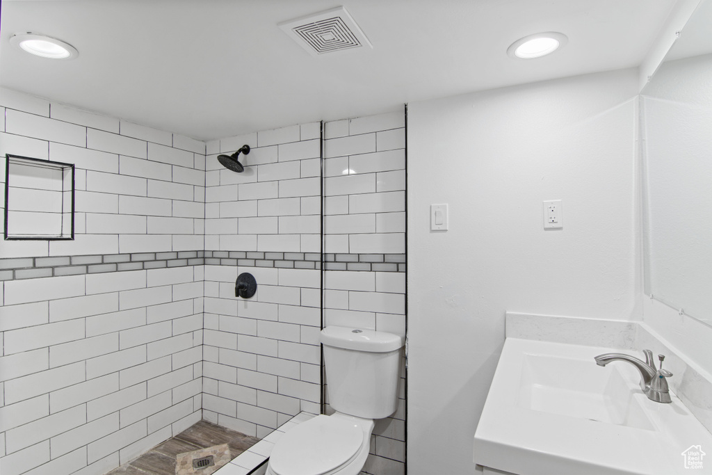 Bathroom featuring toilet, tiled shower, and vanity