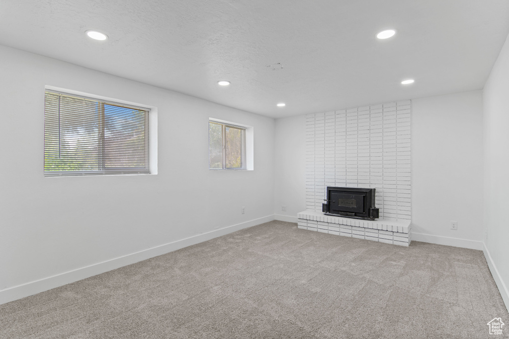 Unfurnished living room with recessed lighting, carpet floors, baseboards, and a fireplace
